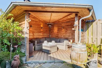a wooden gazebo with a couch and chairs on a deck at De Zonnestraal in Bergen