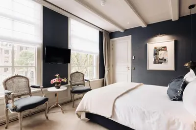 a bedroom with a bed and chairs and a tv at Hotel 717 in Amsterdam
