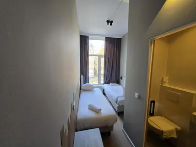 a hotel room with two beds and a window at The Crown Hotel in Amsterdam