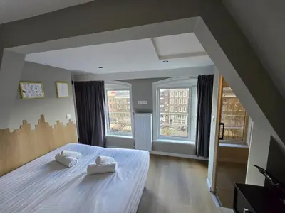 a bedroom with two towels on a bed with two windows at The Crown Hotel in Amsterdam