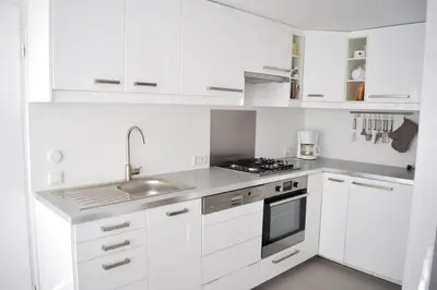 a white kitchen with a sink and a stove at Zeelicht in Noordwijkerhout