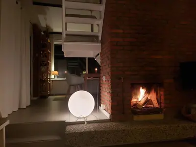 a living room with a brick fireplace and a white chair at Zeelicht in Noordwijkerhout