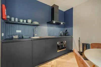 a kitchen with blue walls and a sink and a table at Bens The Highdocks in Amsterdam
