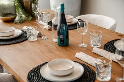 a wooden table with a bottle of wine and glasses at Marley’s Beachhouse - Luxury Apartment with garden in Zandvoort