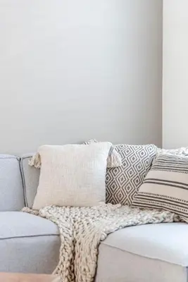 a gray couch with a throw pillow on it at Marley’s Beachhouse - Luxury Apartment with garden in Zandvoort