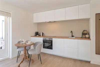 a kitchen with white cabinets and a table with chairs at Yucca Beachhouse in Zandvoort