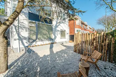 a fence and a bench next to a house at Marley’s Beachhouse - Luxury Guest Room with balcony in Zandvoort