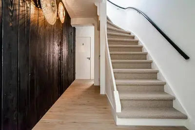 a staircase in a home with white walls and wood floors at Marley’s Beachhouse - Luxury Guest Room with balcony in Zandvoort