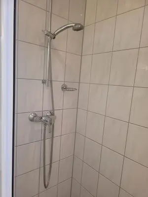 a shower with a shower head in a bathroom at pension canberra in Bergen aan Zee