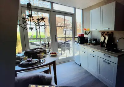 a kitchen with white cabinets and a large window at Wellness Lodge aan de Braassem in Rijnsaterwoude