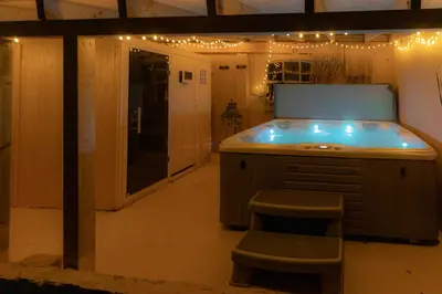 a kitchen with an island with a stool and lights at Wellness Lodge aan de Braassem in Rijnsaterwoude