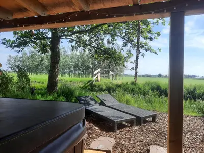 a bench under a pergola with a view of a field at Wellness Lodge aan de Braassem in Rijnsaterwoude