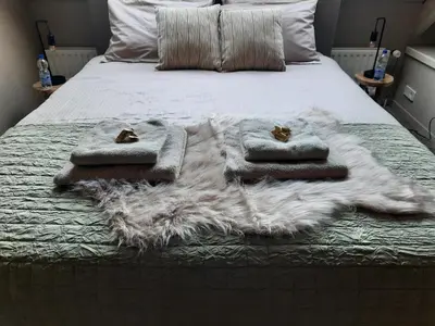 a bed with a white blanket and towels on it at Wellness Lodge aan de Braassem in Rijnsaterwoude