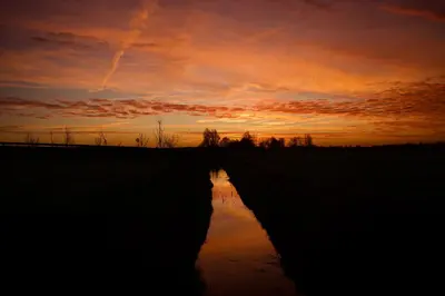 a sunset over a river in a field at Beautiful Countryside house, close to Amsterdam in Broek in Waterland