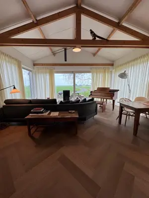 a living room with a black couch and a piano at Beautiful Countryside house, close to Amsterdam in Broek in Waterland