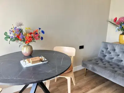 a table with a vase of flowers and a couch at Lovely Spacious Apartment in Zandvoort
