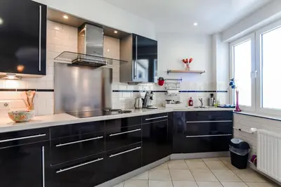 a large kitchen with black cabinets and a window at Studio Tara at the Beach with Private Parking in Zandvoort