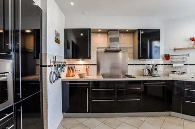 a kitchen with black cabinets and white appliances at Studio Tara at the Beach with Private Parking in Zandvoort