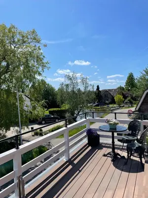 a wooden deck with a table and chairs on it at The Lake Inn in Nieuwkoop