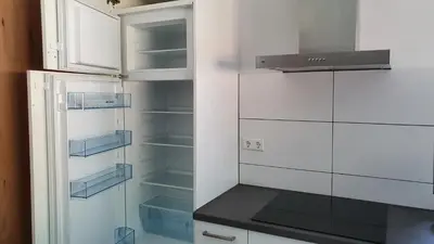 a white refrigerator with empty shelves in a kitchen at Luxe vakantiehuis met omheinde tuin voor hond en kinderen in Dirkshorn