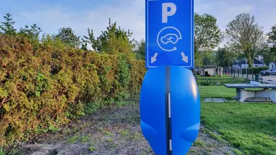 a blue parking sign sitting in the grass at Luxe vakantiehuis met omheinde tuin voor hond en kinderen in Dirkshorn