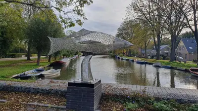 a metal sculpture of a fish on a river at Luxe vakantiehuis met omheinde tuin voor hond en kinderen in Dirkshorn