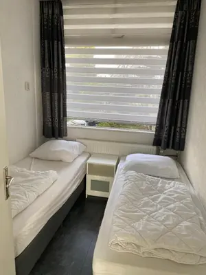 two beds in a small room with a window at De Wulk 27 in Zandvoort