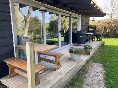 a wooden deck with a table and benches on a house at Holidayhome Geuzenhoeve op de Munnickaij in Schellinkhout