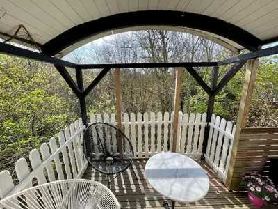 a porch with a white fence and a table and chairs at Pipowagen aan zee in Bergen aan Zee