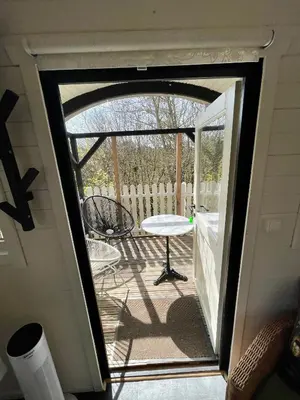 an open door to a patio with a table and chair at Pipowagen aan zee in Bergen aan Zee
