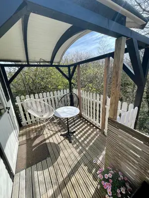 a wooden deck with a table and a chair on it at Pipowagen aan zee in Bergen aan Zee