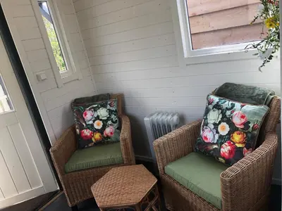 two wicker chairs and a heater in a room at Pipowagen aan zee in Bergen aan Zee