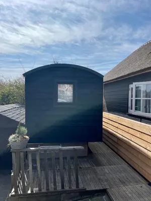 a blue building with a bench on a deck at Pipowagen aan zee in Bergen aan Zee