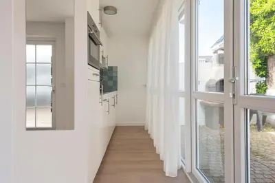 a hallway with white walls and glass doors at Bed & Beach 023 in Zandvoort