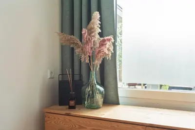 a vase with dried flowers in it sitting on a table at Bed & Beach 023 in Zandvoort