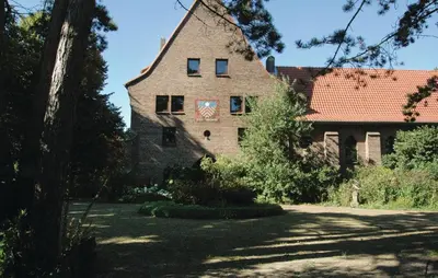 an old stone house with a tree in the foreground at Lovely Home In Egmond Aan Zee With Wifi in Egmond aan Zee