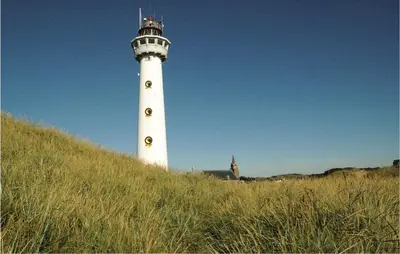 a white lighthouse sitting on top of a grassy hill at Lovely Home In Egmond Aan Zee With Wifi in Egmond aan Zee