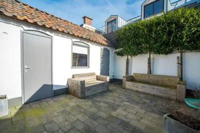 a courtyard with a bench and a house at Sandy's Family Beach House for 2 adults & 2 children in Zandvoort