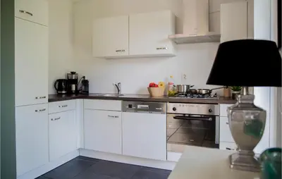 a kitchen with white cabinets and a table with a lamp at Holiday Home Breukelen in Breukelen