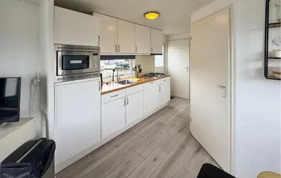 a kitchen with white cabinets and a sink at Chalet in Breukelen