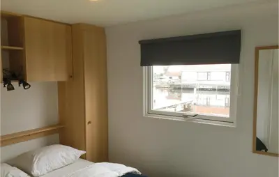 a bedroom with a bed and a window with a blind at Chalet in Breukelen