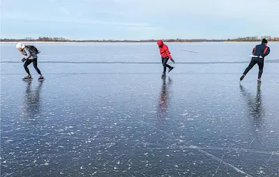 three people are walking on the ice in the water at Chalet in Breukelen