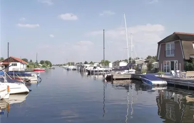 a group of boats docked at a marina with houses at Holiday Home Breukelen Iv in Breukelen