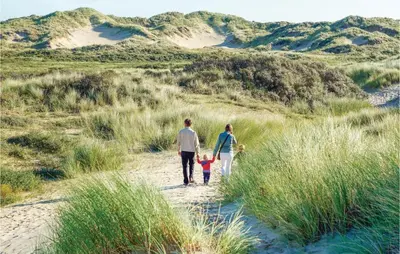 a family walking down a sand path with a dog at Tulp En Zee 6 Persoons in Noordwijk aan Zee