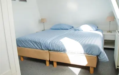 a bedroom with a bed with blue sheets and blue pillows at Tulp En Zee 6 Persoons in Noordwijk aan Zee