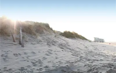 a sandy beach with the sun shining on it at Tulp En Zee 6 Persoons in Noordwijk aan Zee