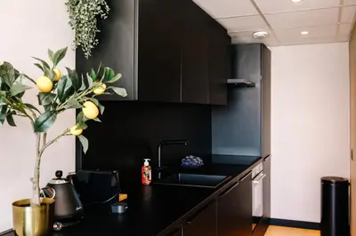 a kitchen with black cabinets and a sink at Apartment Pascalle in Zandvoort