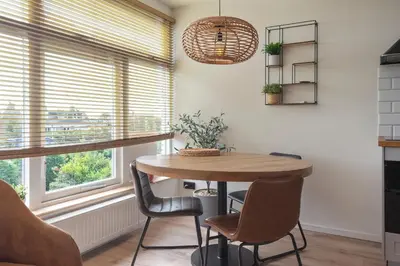 a dining room with a table and chairs and a window at Shell 51 in Zandvoort