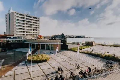 a group of people riding bikes on a sidewalk near the beach at Shell 51 in Zandvoort