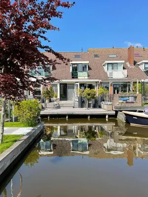 a house with a boat in the water at Guesthouse BedNboot met terras aan het water in Rijpwetering